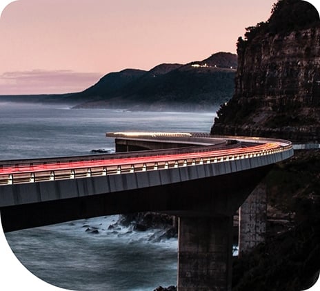 Long exposure of cars driving over a bridge. The bridge is built over a coastline.
